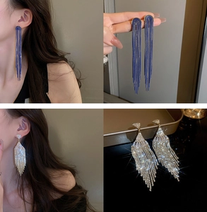Detailed view of U-shaped pearl tassel earrings with rhinestones on a model and tray