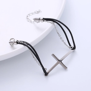 Black woven rope and silver chain bracelet featuring a polished cross on white plate
