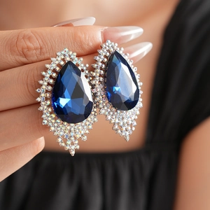 Close-up of royal blue teardrop earrings with shimmering crystal accents and silver finish