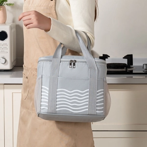 Gray insulated lunch bag with white wave pattern and side mesh pocket held by a hand