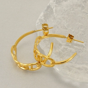 Macro shot of gold-plated stainless steel chain-link earrings on a textured glass tray