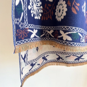 Close-up of floral pattern knit scarf with soft cashmere-like texture and fringed edges