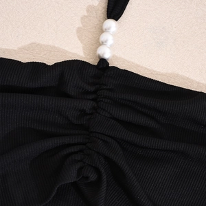 Gros plan sur le tissu côtelé noir avec perles élégantes et détails froncés ajustables