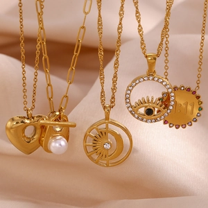 Detailed view of 18K gold plated heart and evil eye charms on a layered necklace set