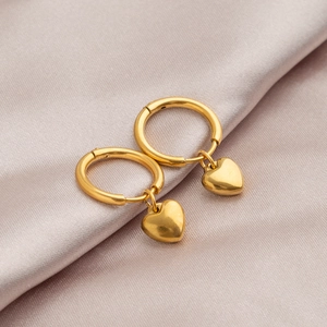 Polished gold heart drop hoop earrings displayed on premium pink silk background