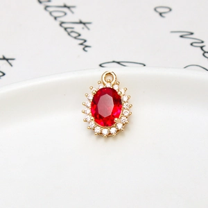 Macro shot of oval ruby glass pendant with white cubic zirconia and gold plating