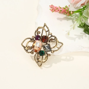 Detail of vintage flower brooch featuring colorful gemstones on a textured stone base