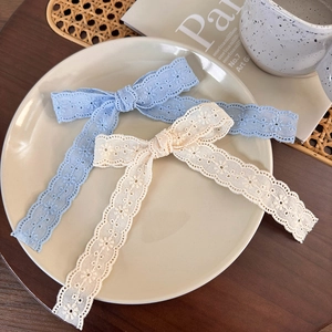 Lace bow hair clips with floral embroidery in blue and beige on a decorative plate