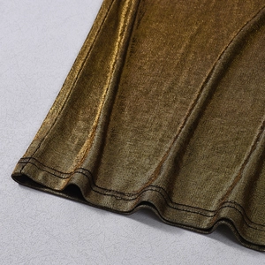 Close-up of golden metallic fabric detail showing shimmering texture and neat double-stitched hem