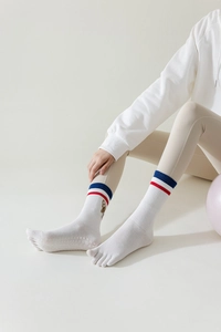 Close-up of white five-toe yoga socks with red-blue stripes and anti-slip dots