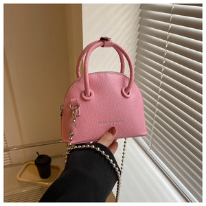 Macro detail of pink pebbled leather mini shell bag with metal bead chain strap