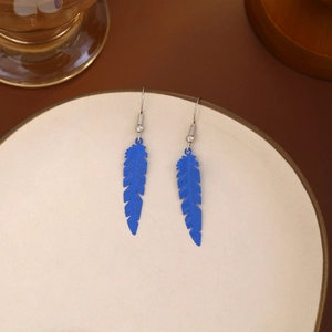 Detail view of colorful blue feather drop earrings placed on a ceramic plate