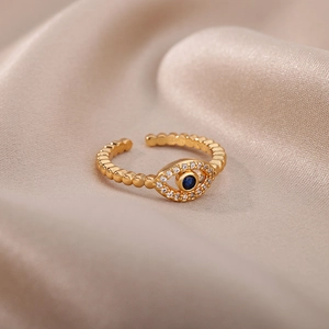 Macro detail of golden Evil Eye ring with blue stone and crystals on silk fabric