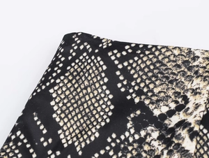 Detailed close-up of snake skin print on high-quality satin midi skirt fabric