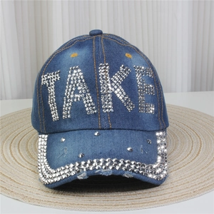 Détail de la casquette en jean avec lettres TAKE en strass et bordure ornée de cristaux