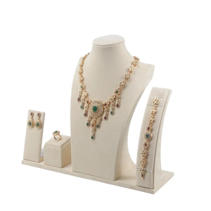 Beige velvet jewelry display stand set with gold necklace and green gemstone earrings