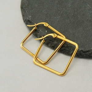 Minimalist geometric square earrings in golden finish on a stone surface