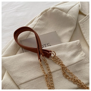 Detail of brown PU leather shoulder strap with golden metal chain on a white blazer