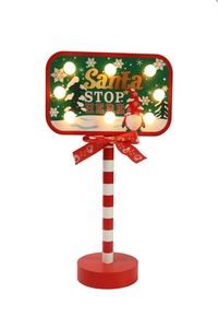 Detail of wooden Santa STOP HERE sign with LED lights and striped pole decoration