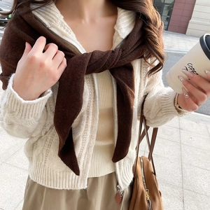 Detailaufnahme der Strickstruktur einer beigen Zopfstrickjacke und eines braunen Schals
