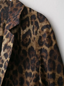 Dettaglio del colletto e della trama del tessuto di un blazer leopardato su sfondo bianco