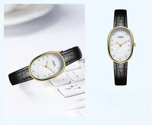 Macro detail of oval gold watch with mother of pearl dial and black leather strap