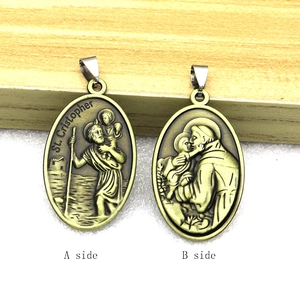 Vintage oval St. Christopher metal charms with embossed religious figures on both sides