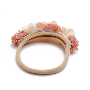 Detail of floral infant headband with peach satin rose and white silk daisies on nylon band