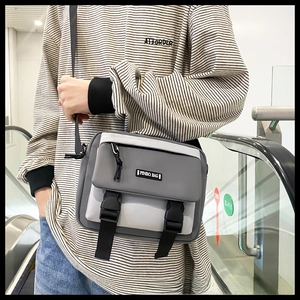 Detail of gray and white crossbody bag with adjustable strap and dual buckle closure