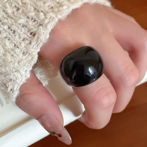 Detail of a large black resin ring with a polished organic shape on a model's finger
