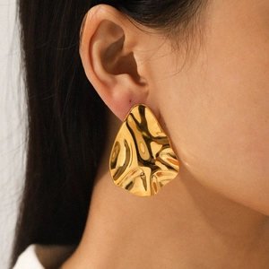 Irregular hammered 18k gold plated stainless steel earrings shown on a model