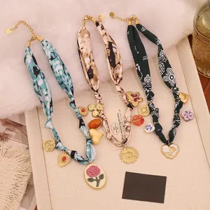 Macro view of silk scarf necklaces with heart pendants and rose charms in retro styles
