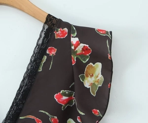 Detailansicht eines Kleides mit Blumenmuster, schwarzem Spitzenbesatz und Stofftextur
