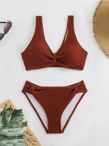 Detailed view of terracotta crinkle fabric bikini set with knot front and summer accessories