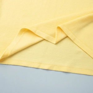 Macro detail of fine knit hemline showing smooth texture on a yellow knit set