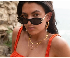 Detail of vintage oval sunglasses with gold horsebit buckle and pearl earrings
