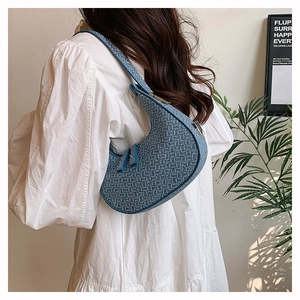 Detailed view of a blue woven crescent bag styled with a white puff-sleeve dress