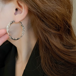 Close-up of silver geometric layered hoop earrings worn by a model in a stylish pose
