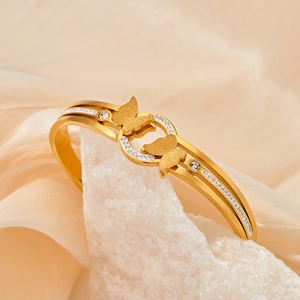 Elegant gold stainless steel butterfly bangle with crystal stones on satin background