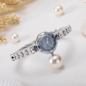 Detail of luxury women's watch with mother-of-pearl dial and hanging pearl pendant