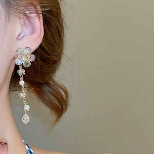 Detailed view of floral crystal tassel earrings with pearls on a model side profile
