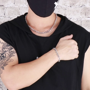 Street style view of a silver curb chain necklace and bracelet set on a model in black