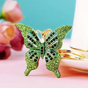 Detailed macro view of gold butterfly keychain with green and black rhinestones