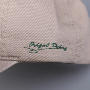 Close-up of green Original Design embroidery on beige twill cotton baseball cap