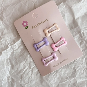 Pink bone-shaped hair clips set with star accents on display card for women