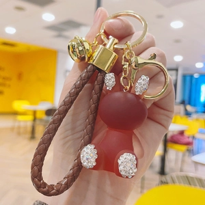 Detail of red resin bear keychain with rhinestones and brown braided leather strap