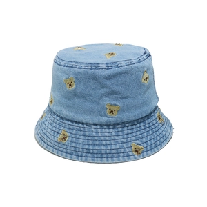 Close-up of light blue denim bucket hat with detailed yellow bear embroidery patterns