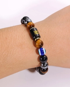 Detail of tiger eye and black obsidian beaded bracelet with gold letter M charm on wrist