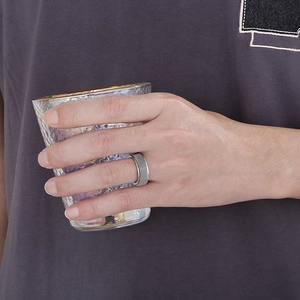 Silver rotatable spinner ring with woven mesh texture on hand holding a glass