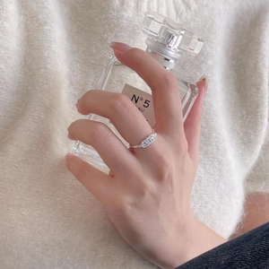 Minimalist 925 sterling silver ring with embossed pattern worn by hand holding a bottle